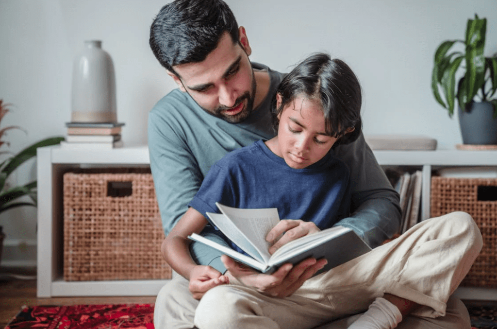 Father sat with child on his lap reading a book