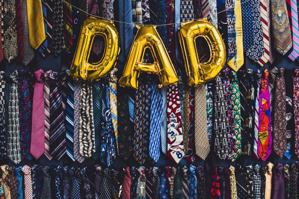 Dad spelled out in balloons in front of a wall of ties