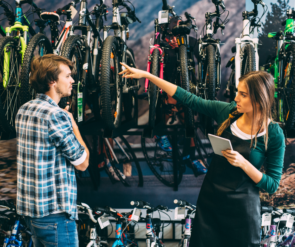 Bike Store Employee using a Mobile Device whilst Navigating the Store with a Customer