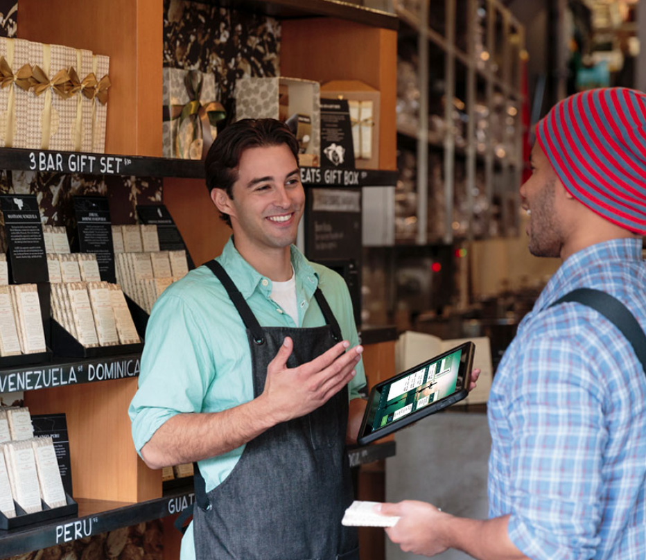 A Store Employee Talking to a Customer Whilst Holding the Mobile Point of Sale with Retail Pro on